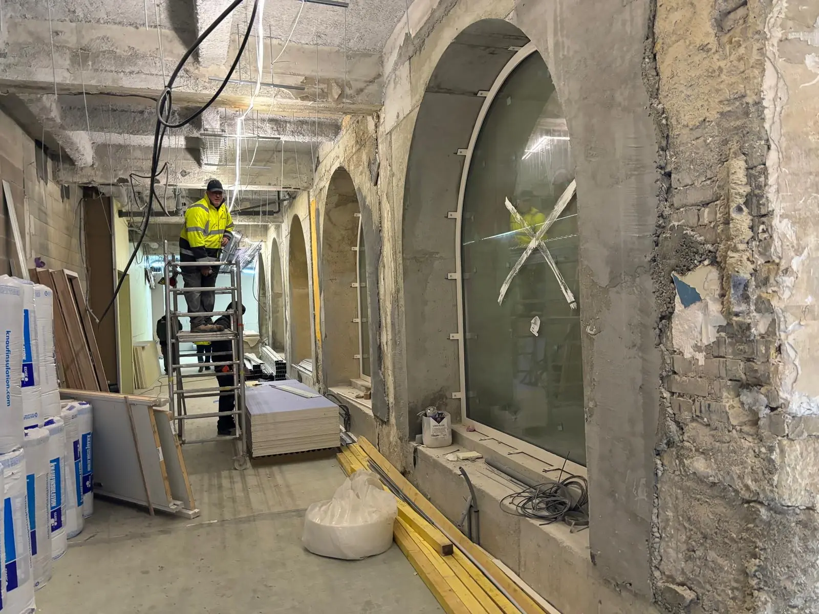 Compagnon sur escabeau dans la galerie voûtée en cours de reprise