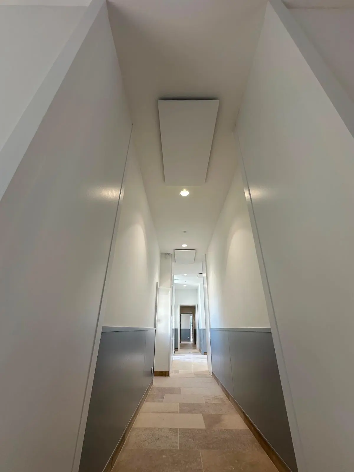 Couloir étroit à plafond blanc continu, éclairage encastré affleurant