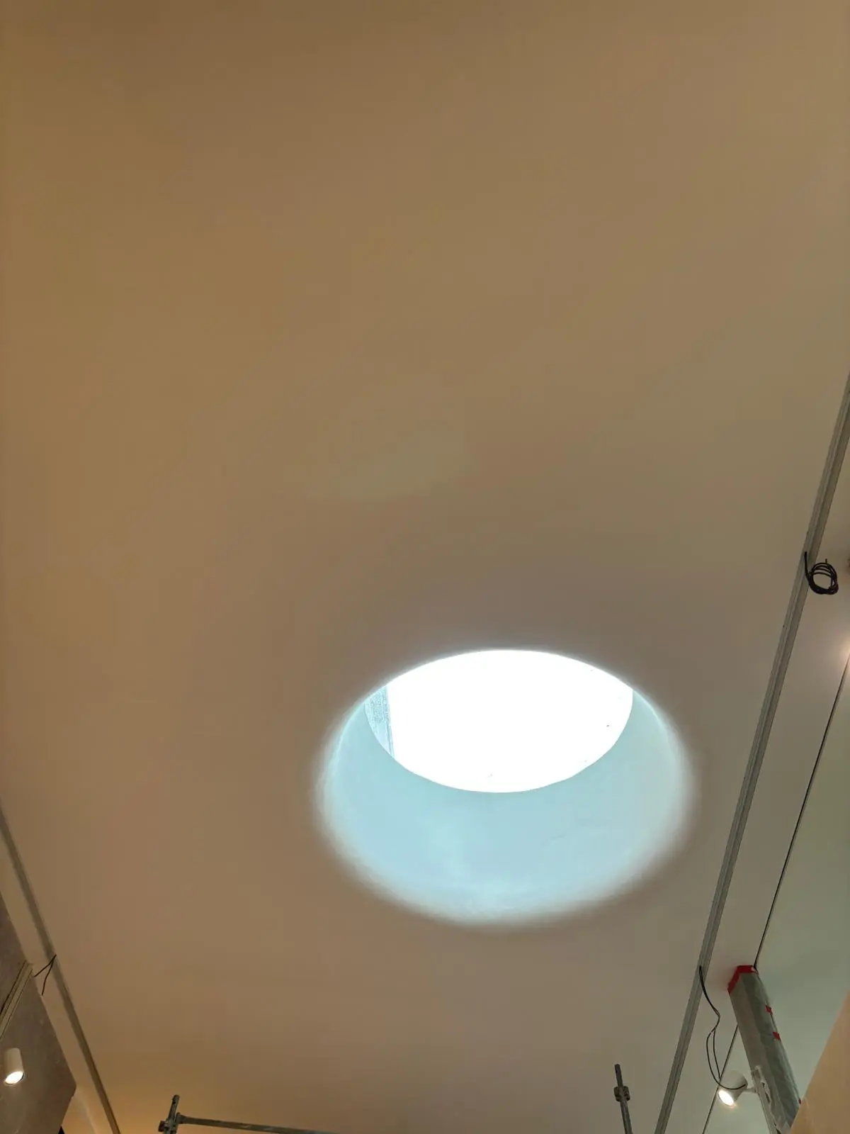 Détail d'un plafond blanc sans joint percé d'un oculus lumineux