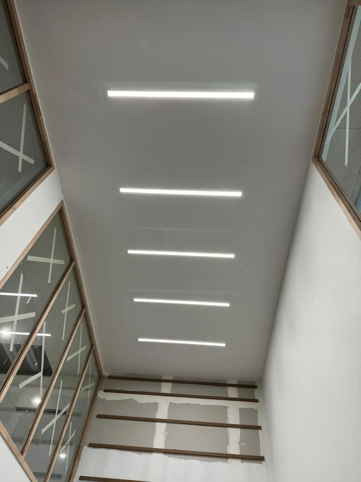 Vue vers le haut d'un plafond de circulation rythmé par des réglettes linéaires