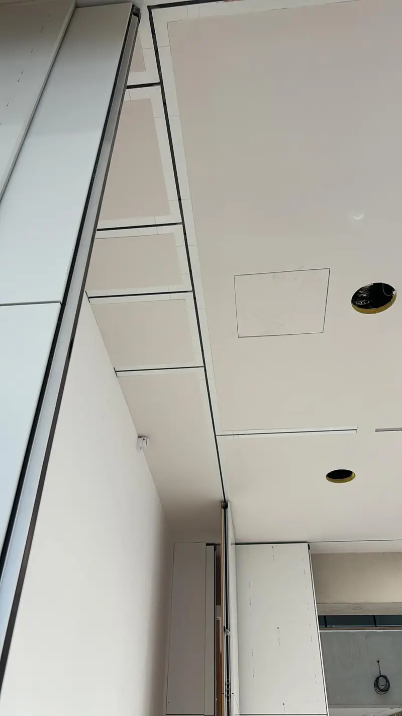 Détail de plafond blanc avec trappe de visite affleurante et spot encastré