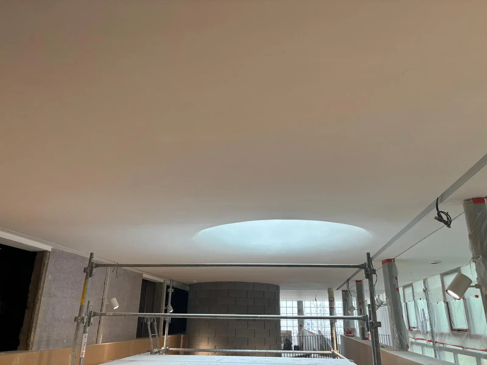 Hall sous plafond continu percé d'un large oculus rétroéclairé, garde-corps de passerelle