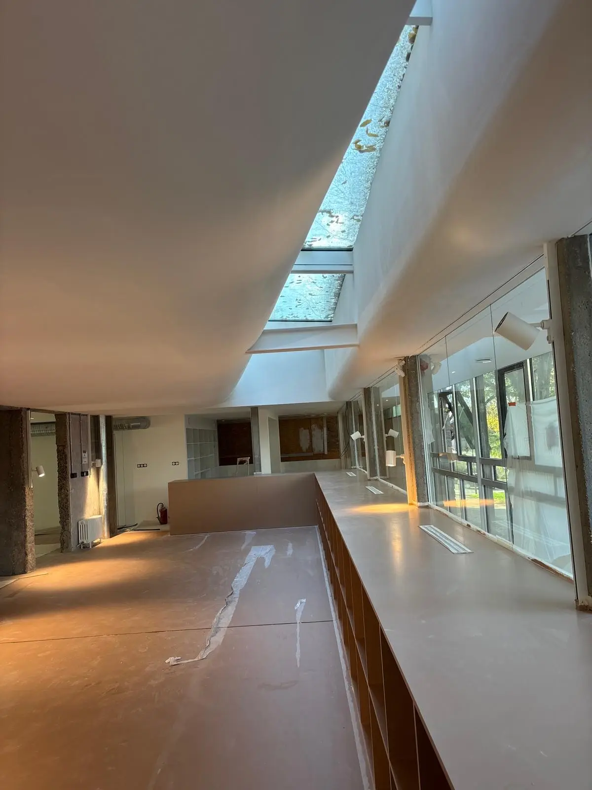 Passerelle intérieure sous plafond blanc continu, verrière zénithale