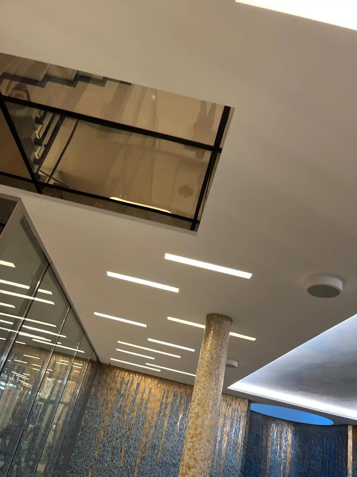 Plafond de hall percé de réglettes lumineuses, retombée près de la verrière