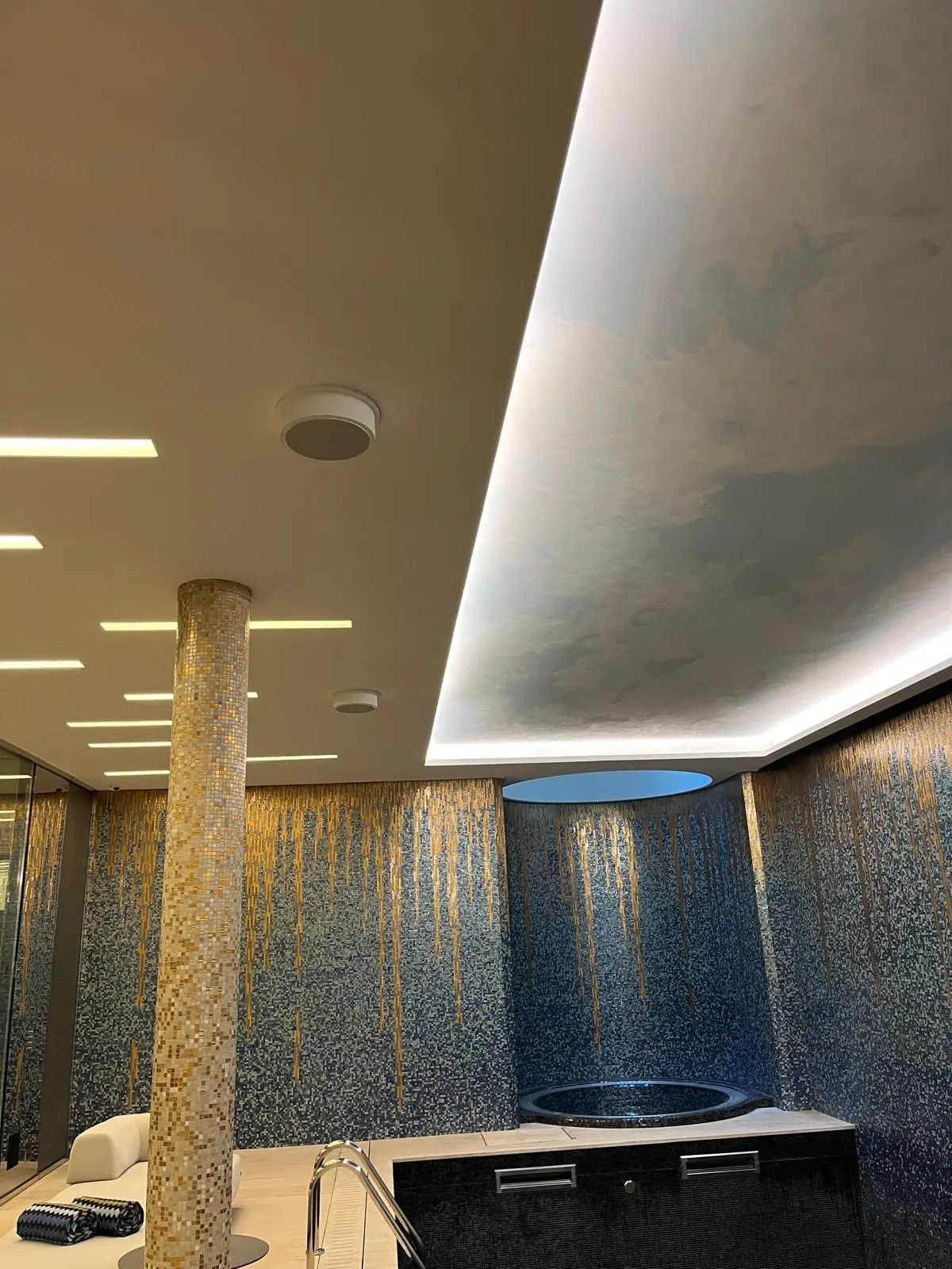 Retombée courbe rétroéclairée au-dessus d'un comptoir, colonne habillée de mosaïque