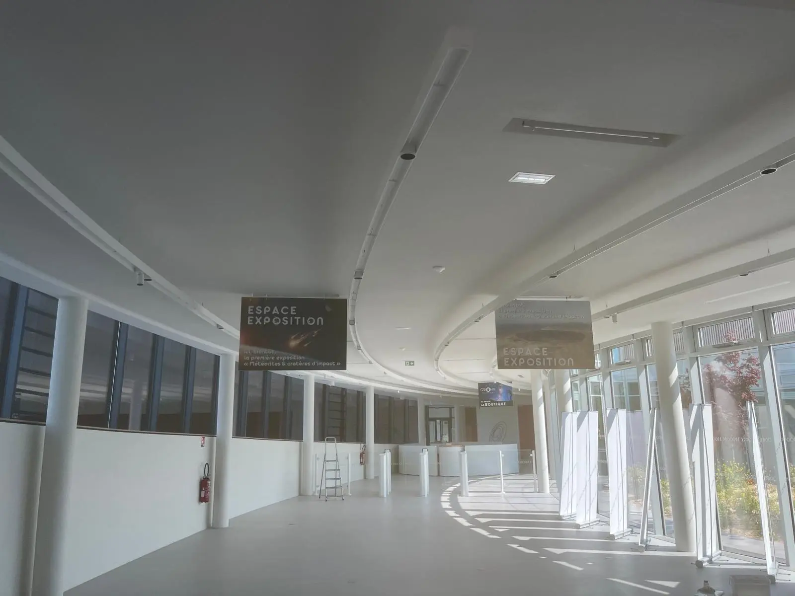 Galerie sous plafond ondulé blanc, signalétique suspendue