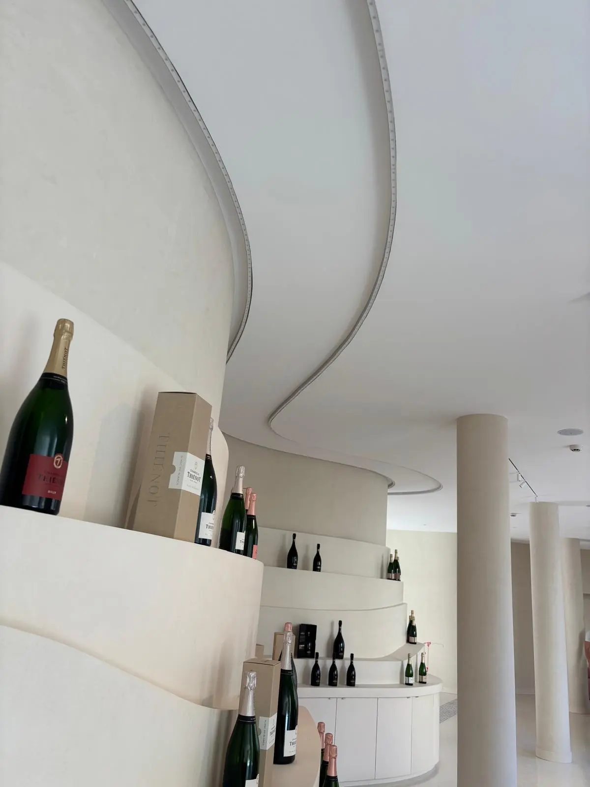 Boutique aux étagères courbes blanches présentant des bouteilles de champagne