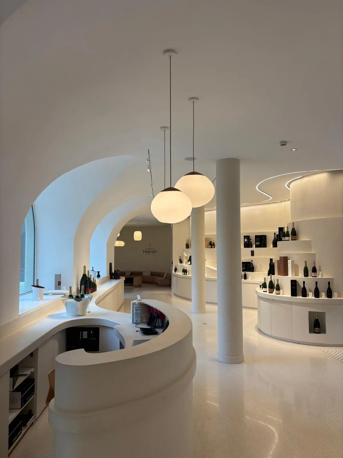 Boutique voûtée avec comptoir courbe blanc et suspensions sphériques
