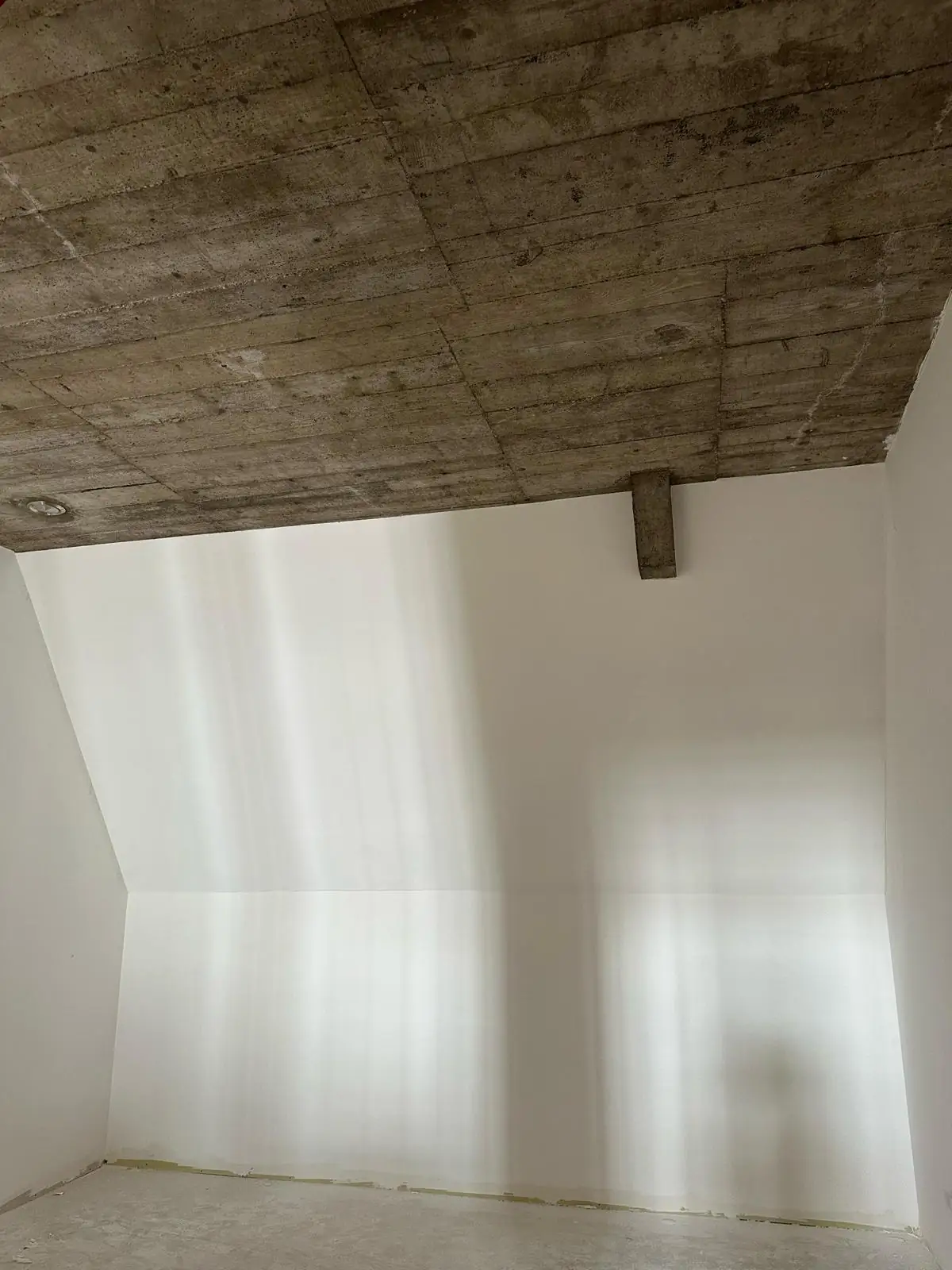 Mur des combles plaqué et lissé sous la dalle de béton coffrée en planches, pied de cloison encore en plaque