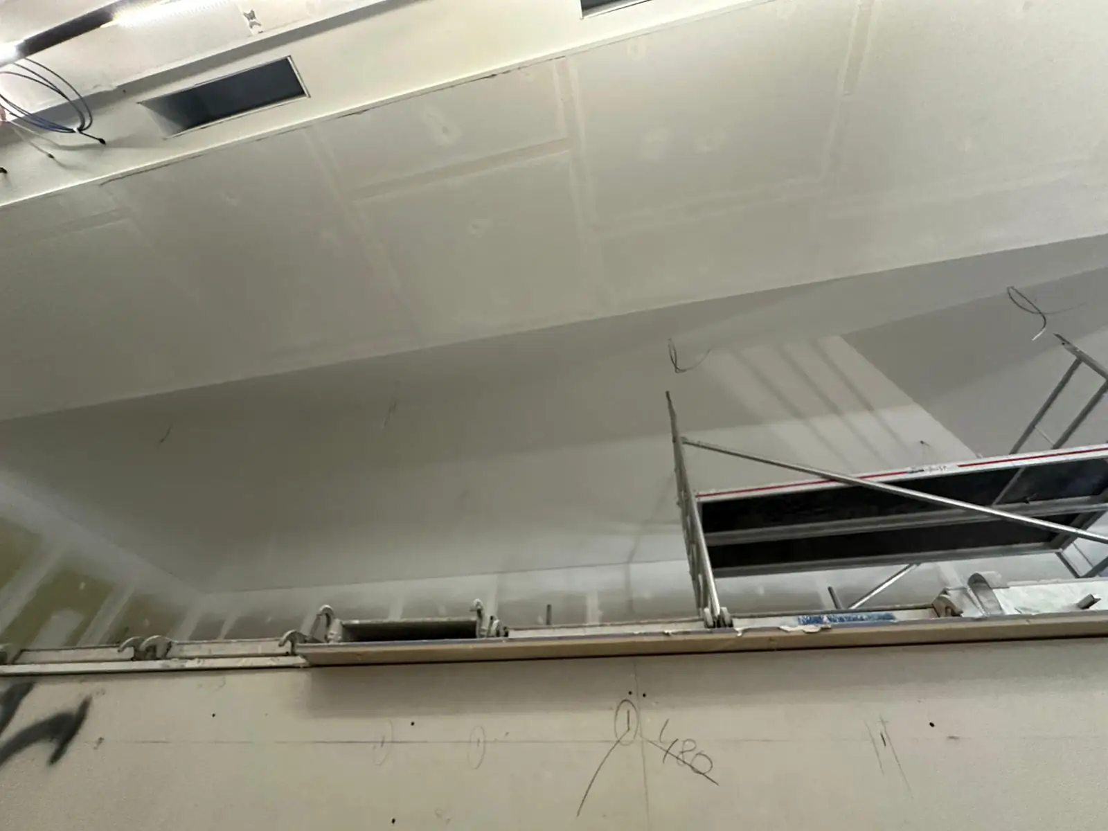 Plafond plaqué sur toute la longueur d'un plateau, calepinage encore lisible avant enduit, réservation ouverte au droit de l'échafaudage