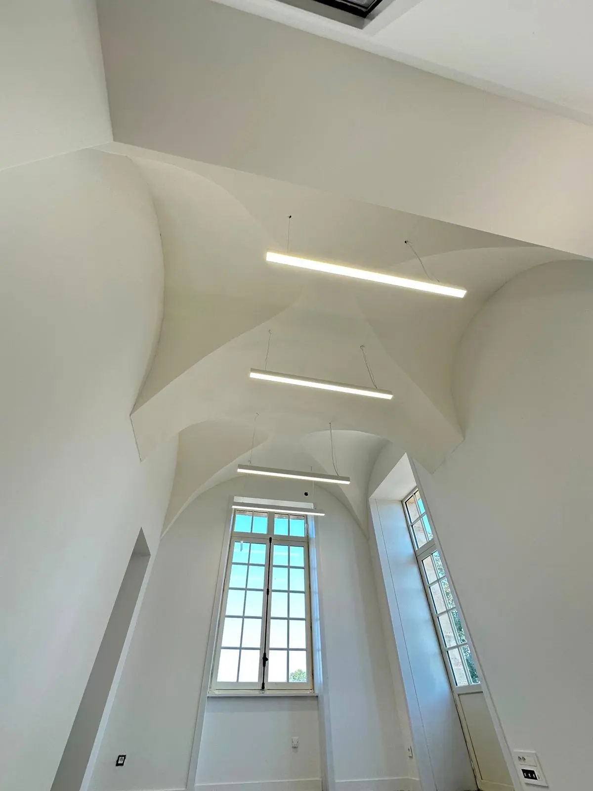 Voûte blanche continue traversée d'une réglette lumineuse linéaire