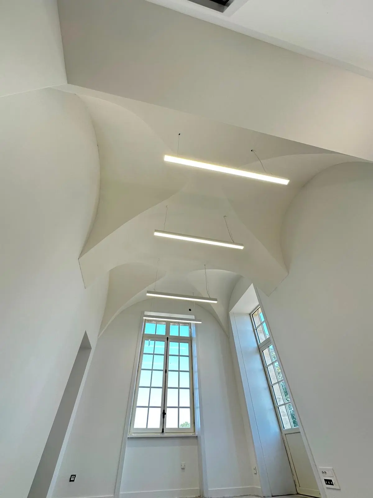 Voûte d'arêtes blanche avec deux réglettes linéaires encastrées, fenêtre haute
