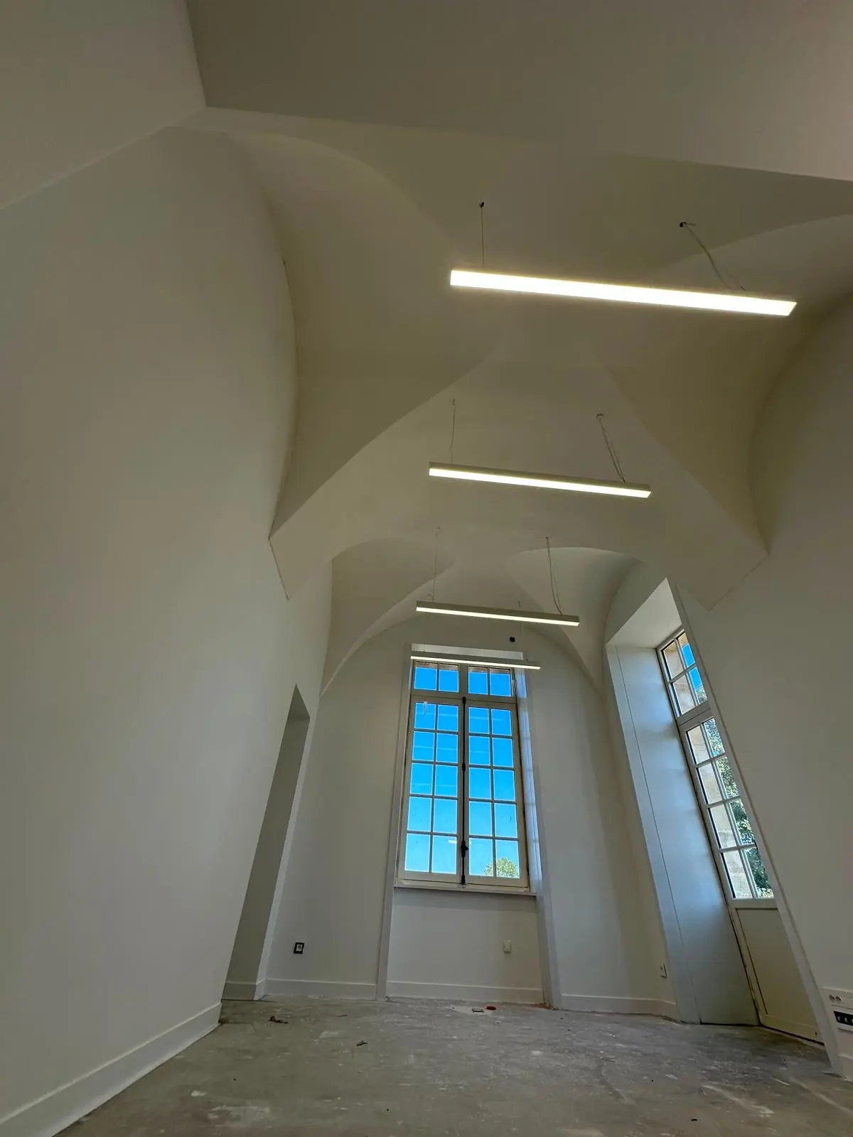 Voûte blanche et réglette lumineuse au-dessus d'une fenêtre cintrée