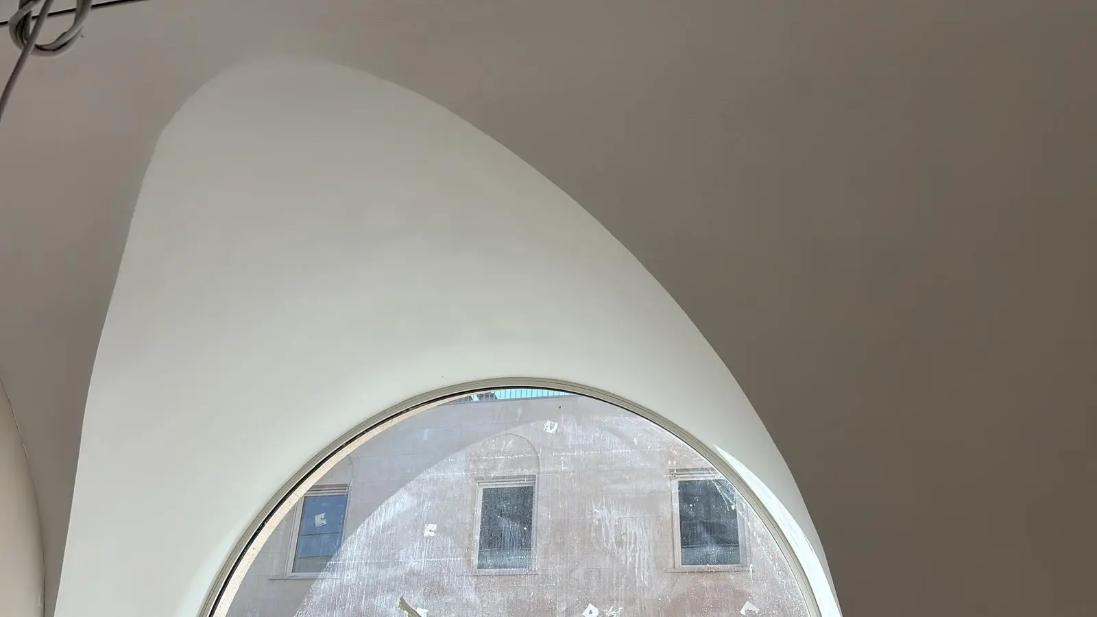 Grande arche courbe blanche encadrant une verrière circulaire
